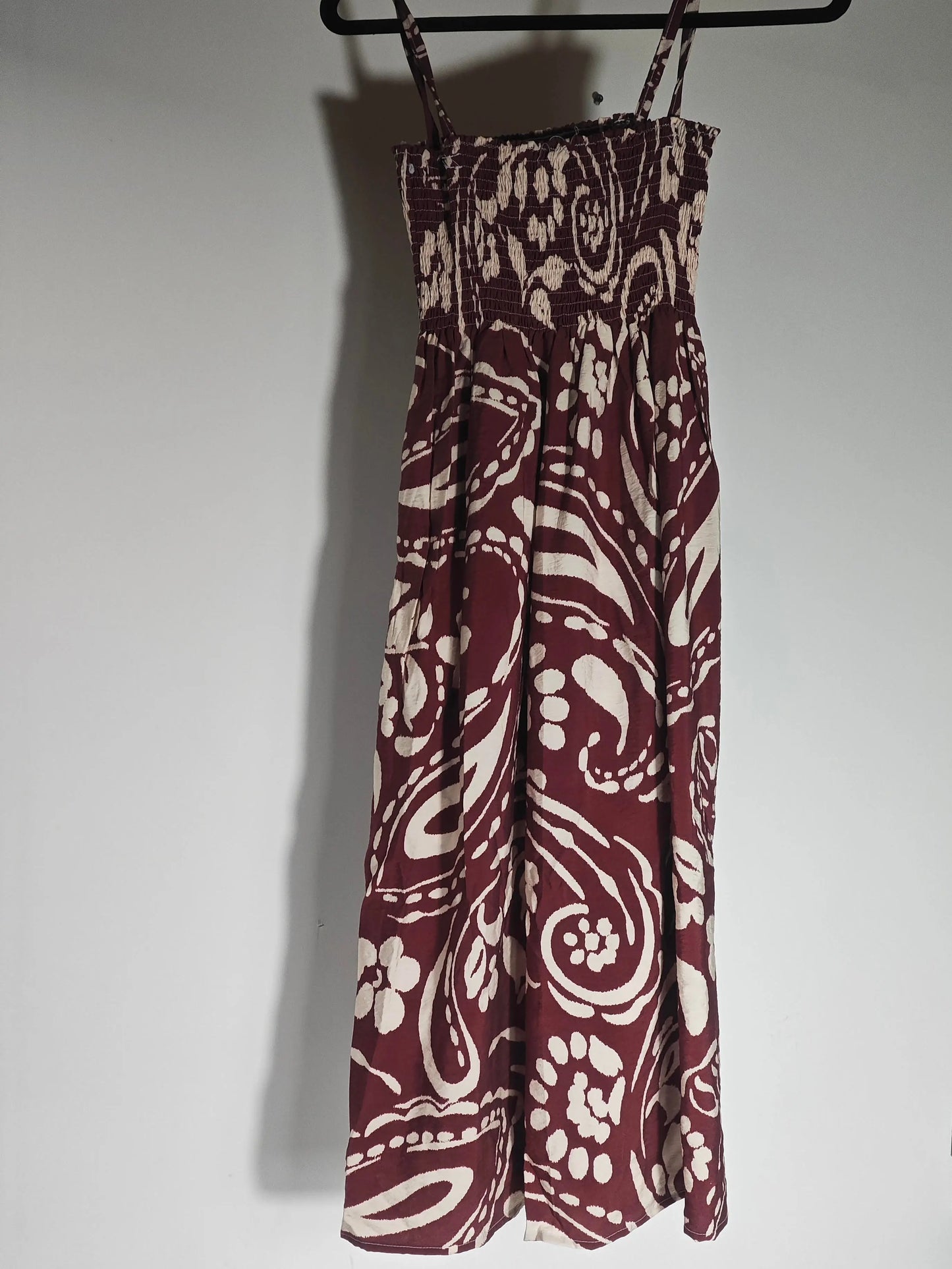 Robe taille unique bordeaux et beige d'Upstyle Destock, avec un imprimé cachemire all-over, suspendue à un cintre.