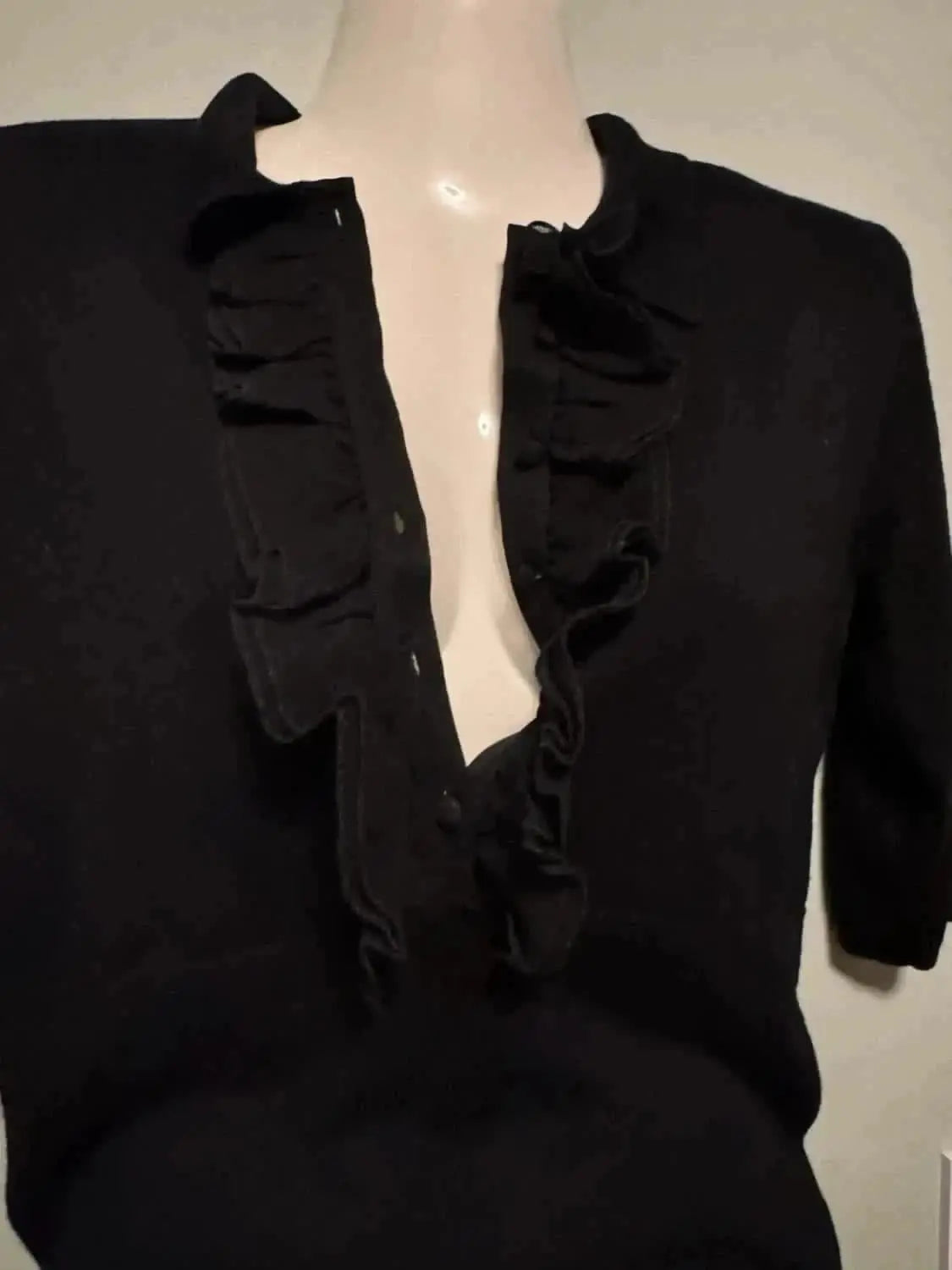 Blouse noire à volants de Kookai, manches courtes, style chic et intemporel sur mannequin.
