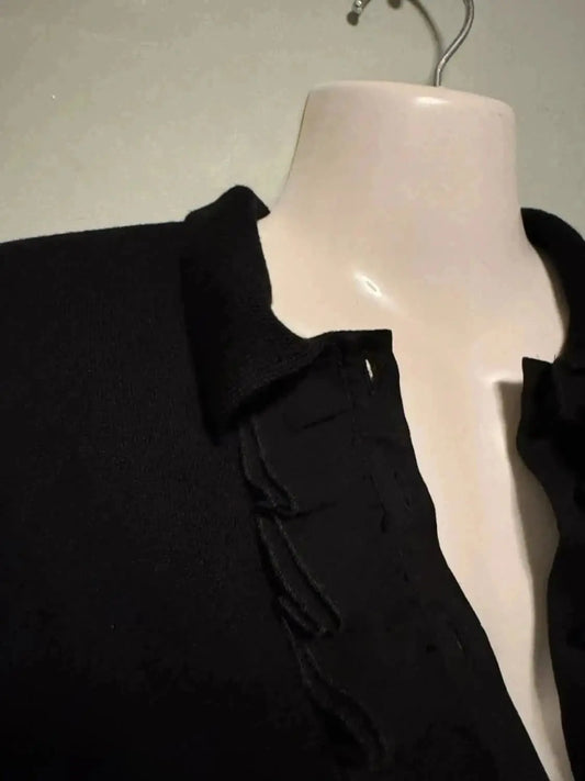 Blouse noire à détails volants de Kookai, style chic intemporel sur un cintre.
