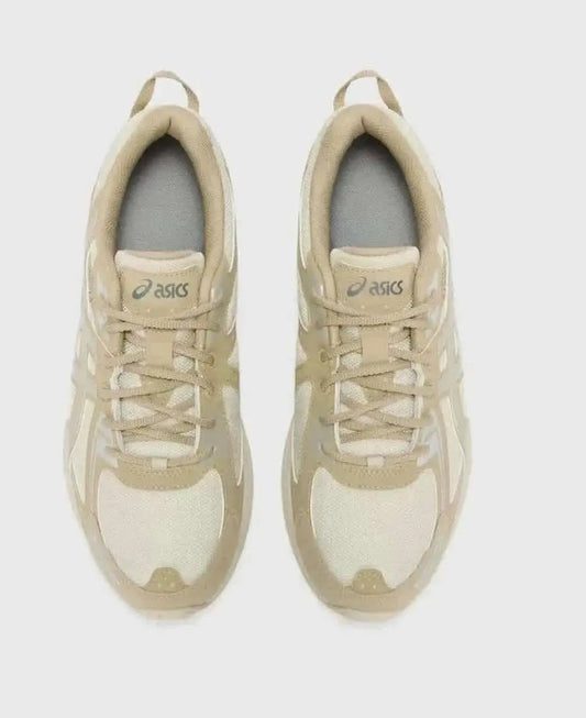 Chaussures de running beiges par Asics, avec lacets et semelle épaisse.
