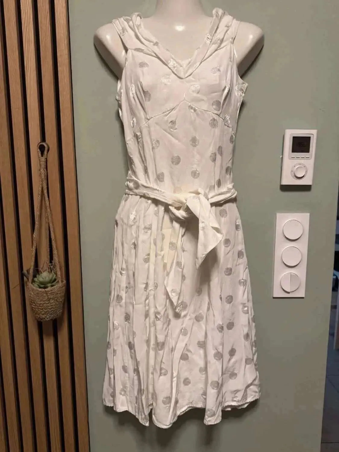 Robe blanche à pois argentés de NAF NAF, ceinturée, sur un mannequin.