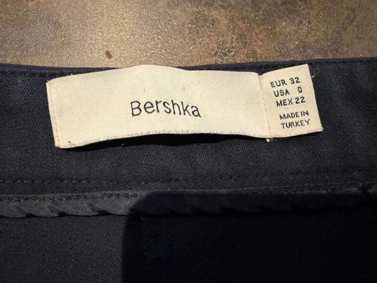 Pantalon bleu marine de Bershka, avec une étiquette indiquant les tailles EUR 32, USA 0 et MEX 22, fabriqué en Turquie.