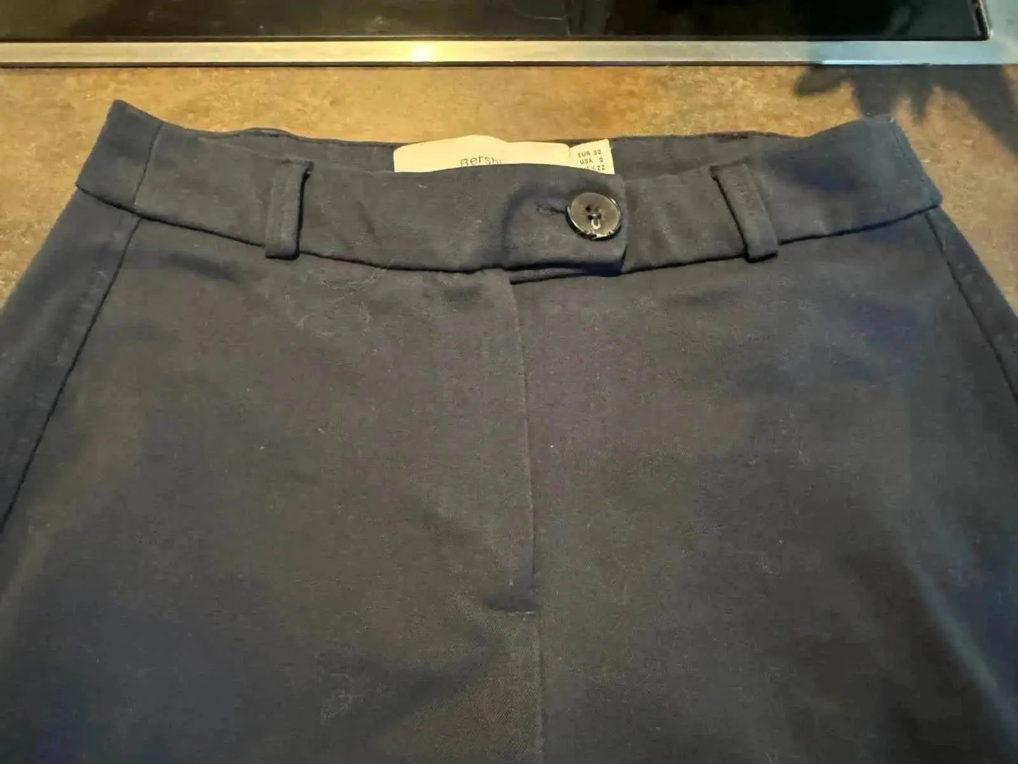 Pantalon bleu marine de Bershka, coupe droite avec fermeture boutonnée et passants de ceinture.