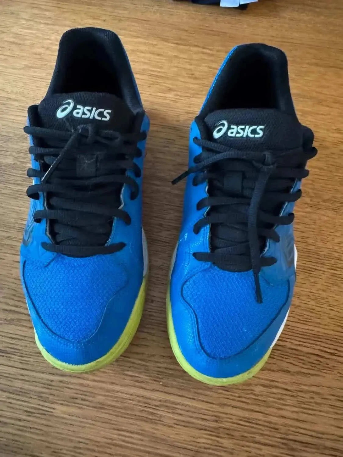 Chaussures de sport bleues par ASICS, avec des lacets noirs et une semelle jaune.

