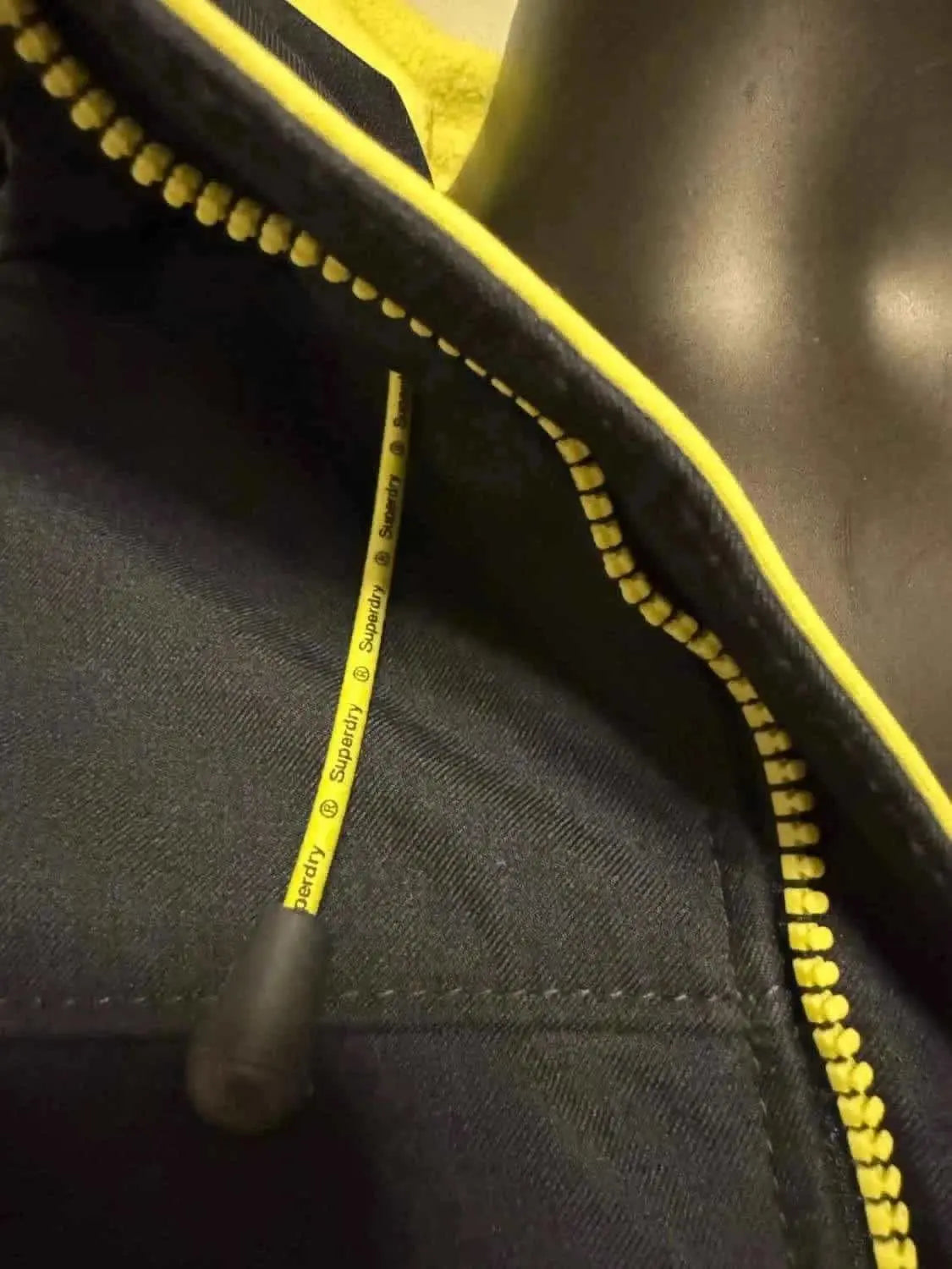 Veste bleue avec fermeture éclair jaune de Superdry, avec tirette à cordon logotée.