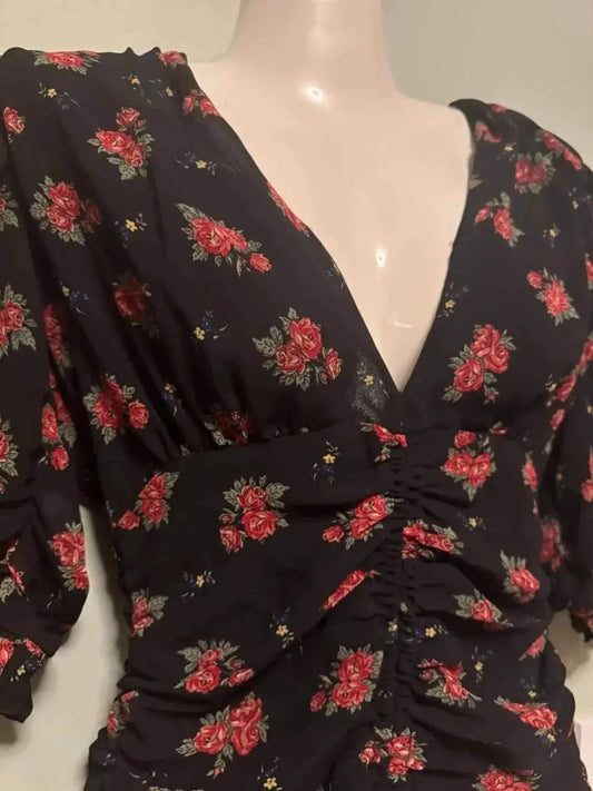Robe Zara noire à fleurs, de Zara, avec un décolleté en V et des fronces sur le devant.

