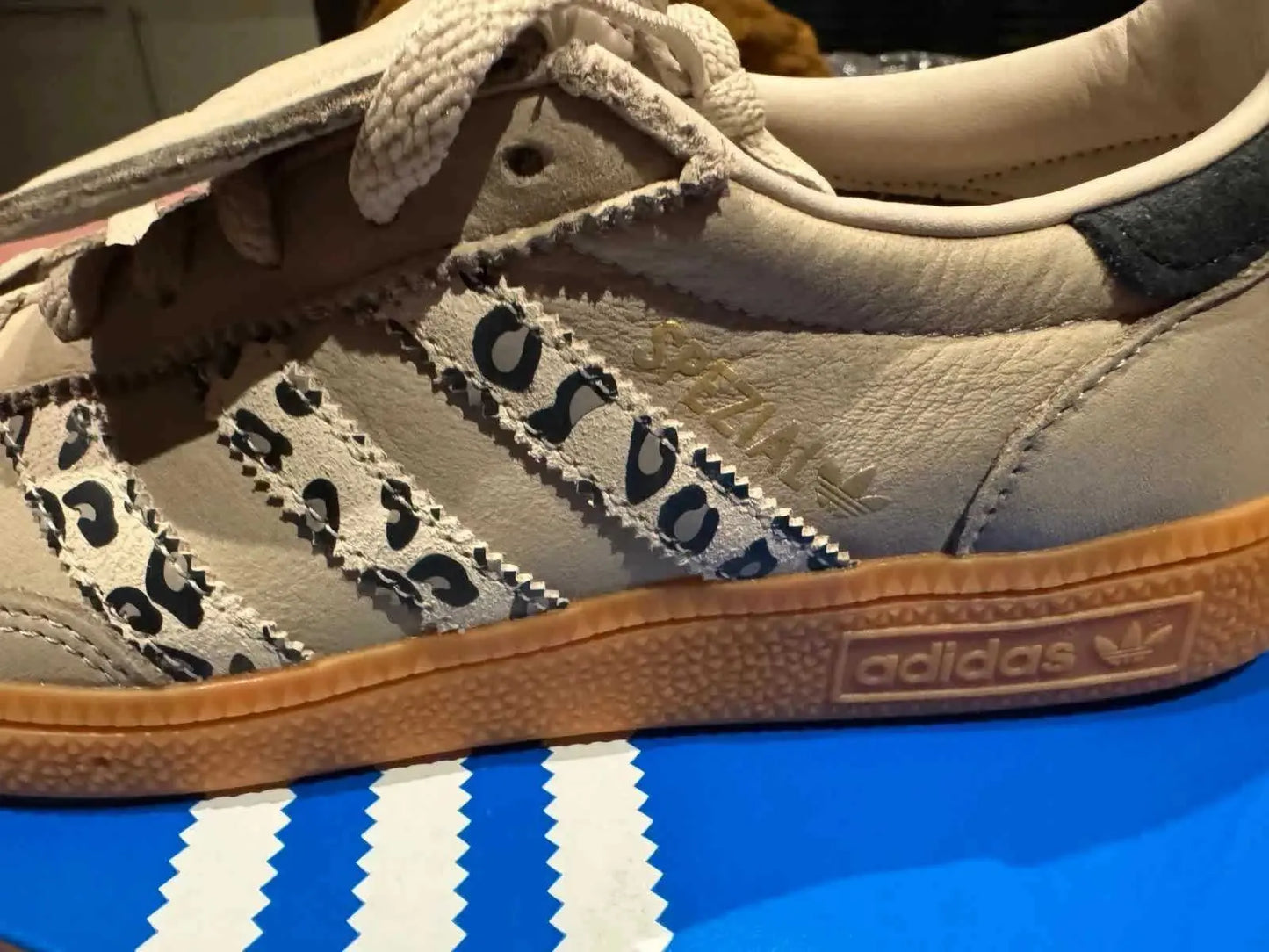 Chaussure de sport beige en cuir d'Adidas, avec motif léopard sur les trois bandes latérales et semelle gomme.
