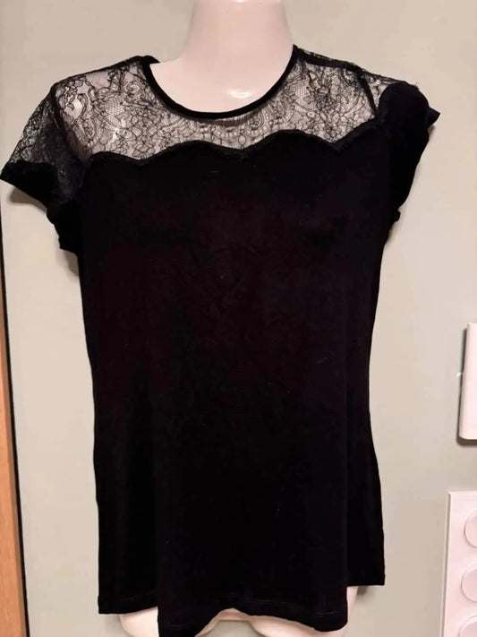 Haut noir avec empiècement en dentelle de Maje, manches courtes en dentelle florale sur un mannequin.
