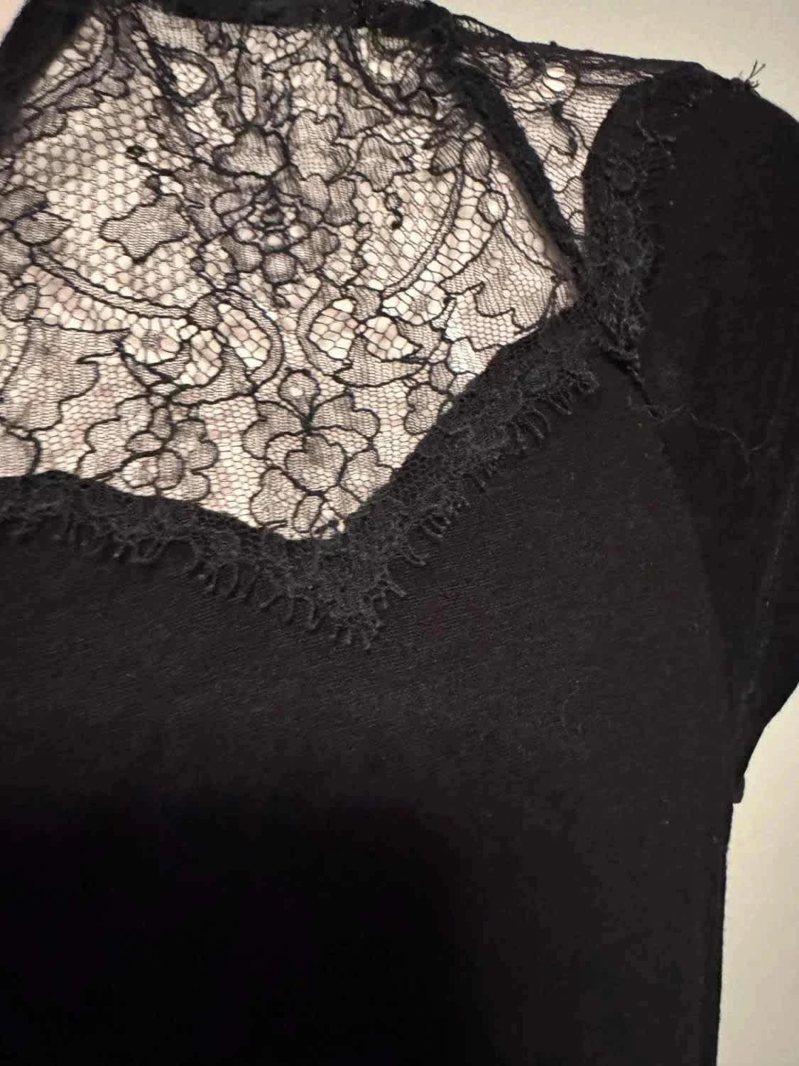 Haut noir à empiècement en dentelle, de Maje, avec motif floral délicat et finitions festonnées.
