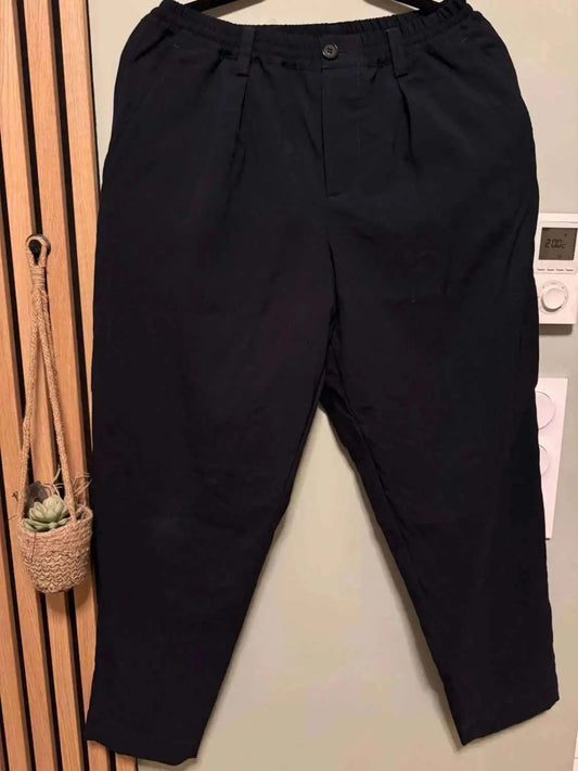 Pantalon ample noir de Marni, avec une taille élastiquée et des plis devant, sur un fond neutre.
