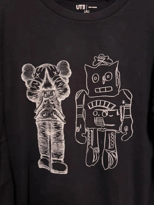 T-shirt noir de Uniqlo, collaboration avec KAWS et Andy Warhol, orné de motifs graphiques blancs.
