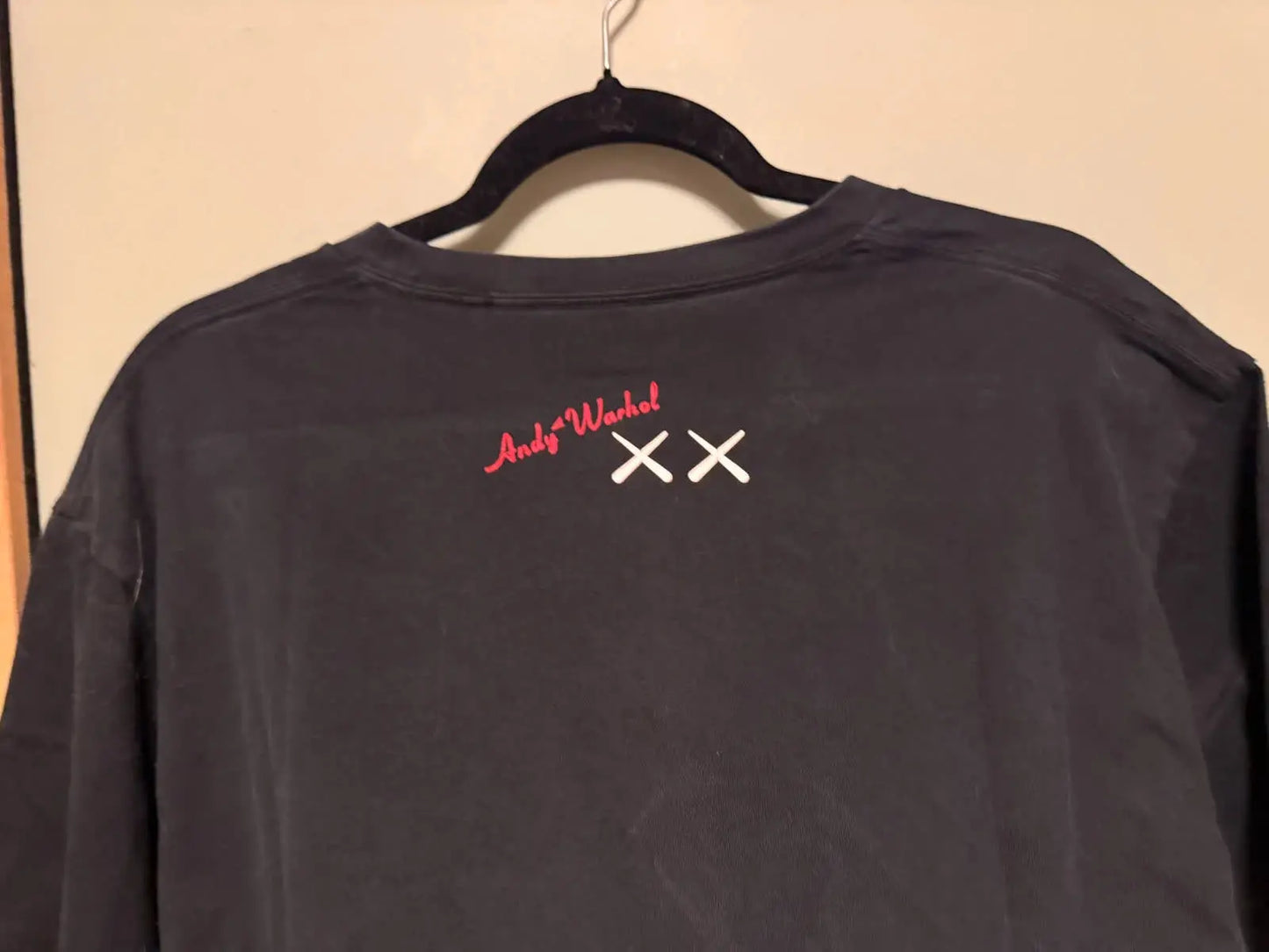 T-shirt noir de Uniqlo, collaboration KAWS et Andy Warhol, avec des motifs graphiques brodés au dos.