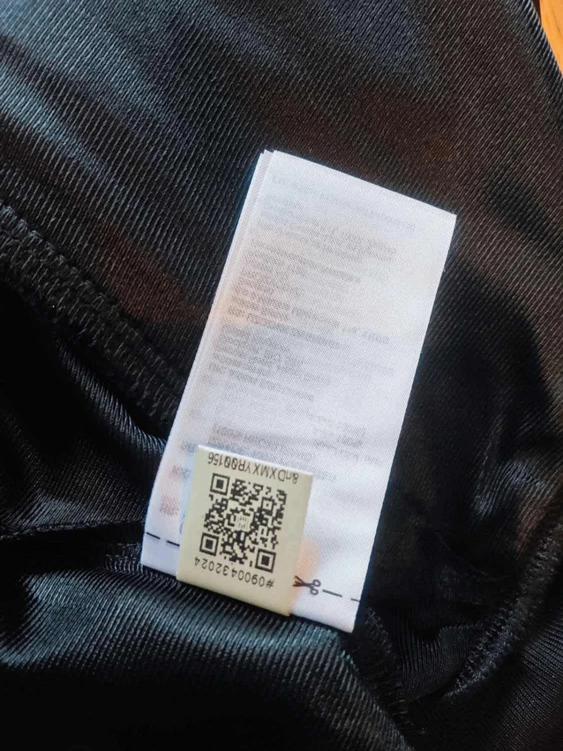 Veste de survêtement noire Adidas Originals avec étiquette d'instructions de lavage et code QR.
