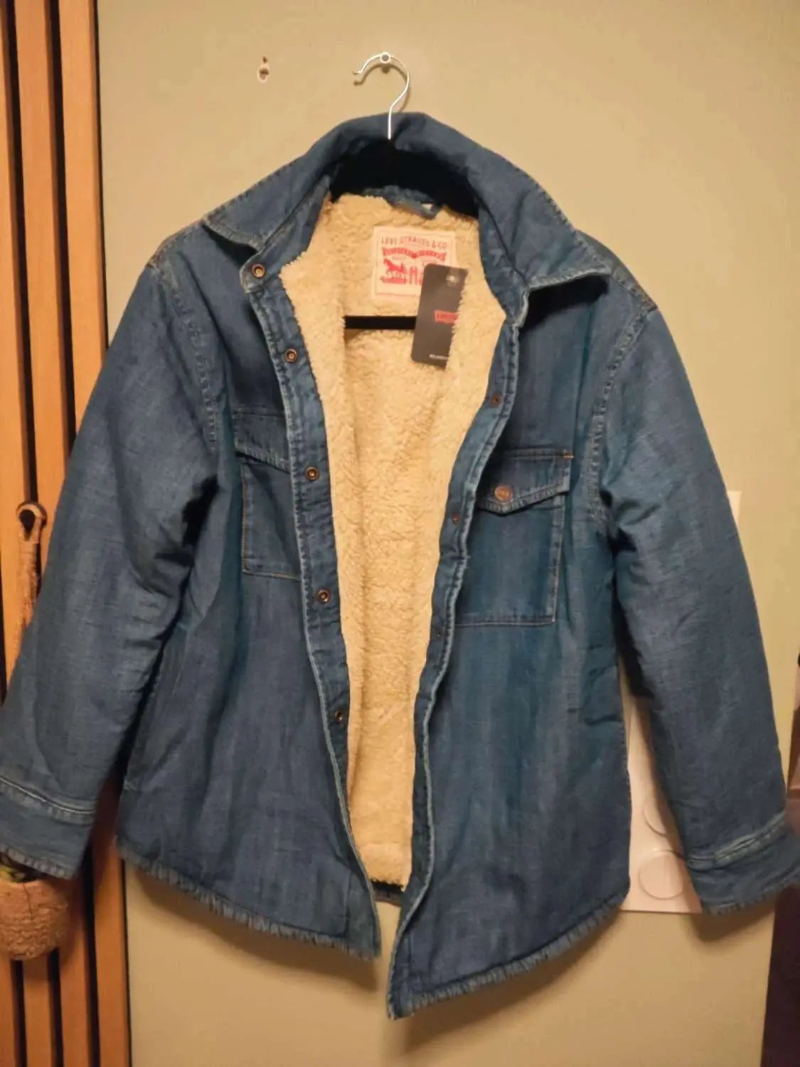 Veste en jean bleu fourrée sherpa de Levi's, avec poches poitrine boutonnées et étiquette attachée.
