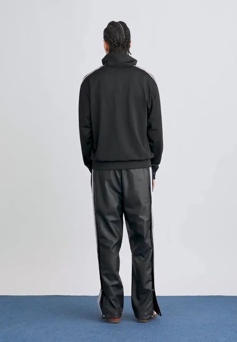 Veste de survêtement noire à rayures blanches d'Adidas, avec un pantalon assorti et tresses.
